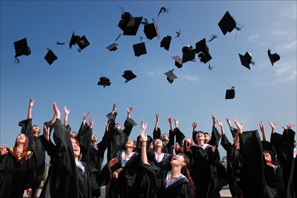 Graduating students in gowns celebrating and tossing their caps
